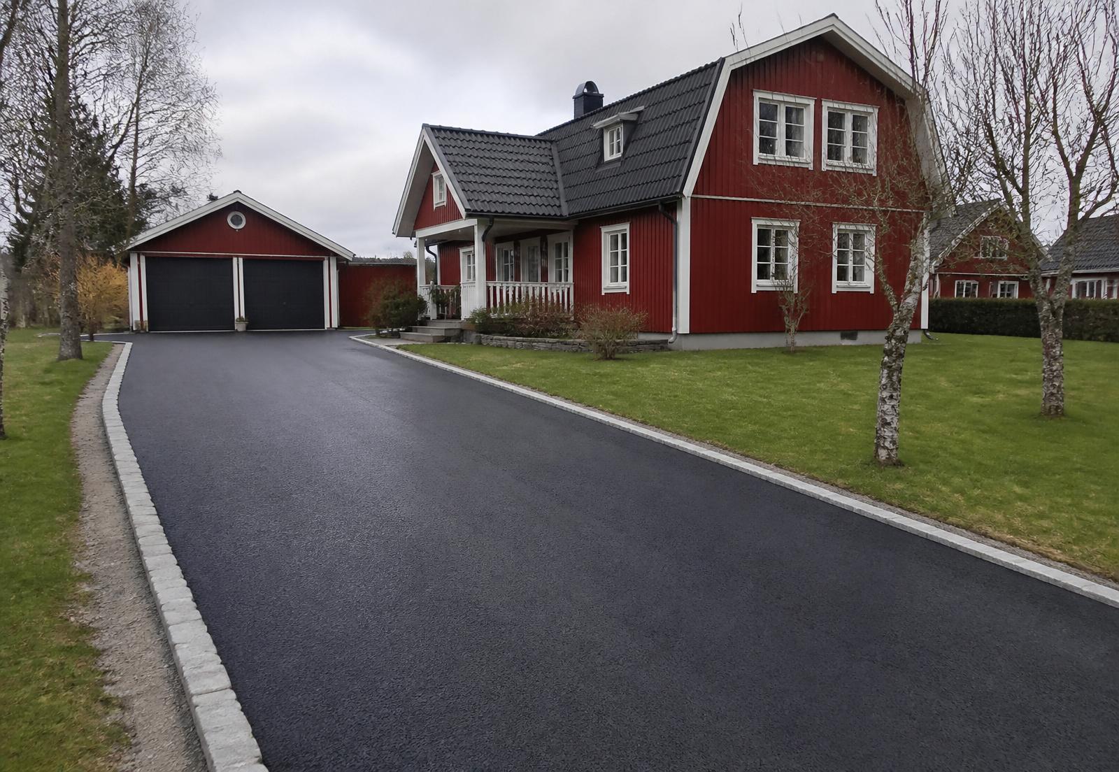 Nyasfalterad uppfart med granitkantsten framför en Falu-röd villa i Bankeryd utanför Jönköping